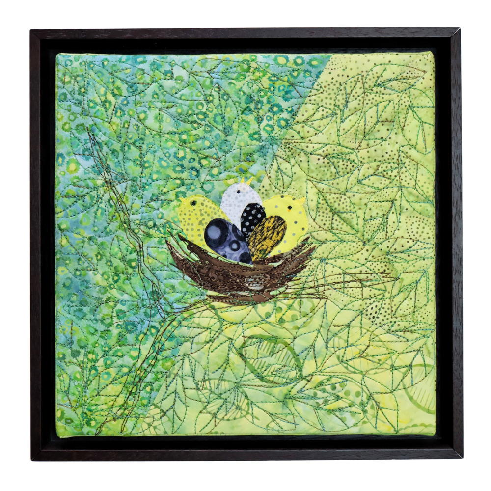 Framed artwork of birds in a nest on a green leafy background