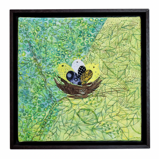 Framed artwork of birds in a nest on a green leafy background